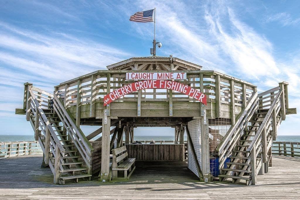 a wooden fishing pier with a two observation deck and an american flag on top