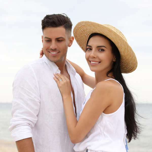 a smiling couple walking on the beach wearing striped outfits