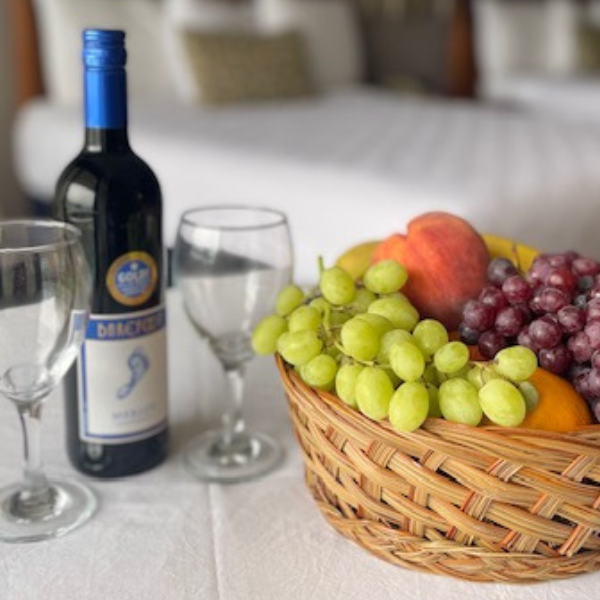 a bottle of wine and a fruit basket with grapes and bananas