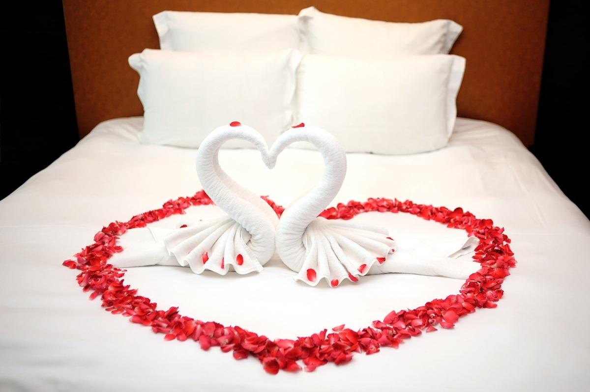Rose petals on the bed with towels swans kissing