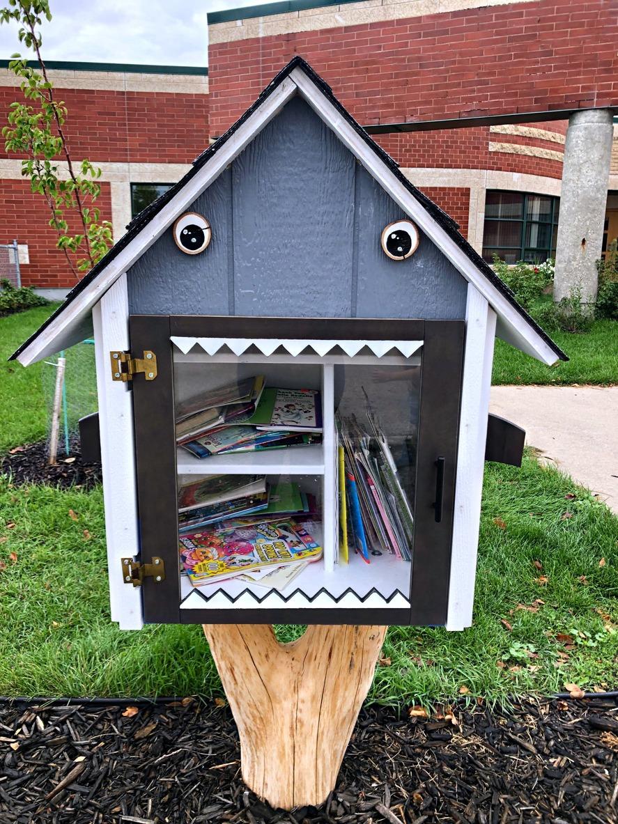 a little free library that looks like a shark found near a shopping center filled with books