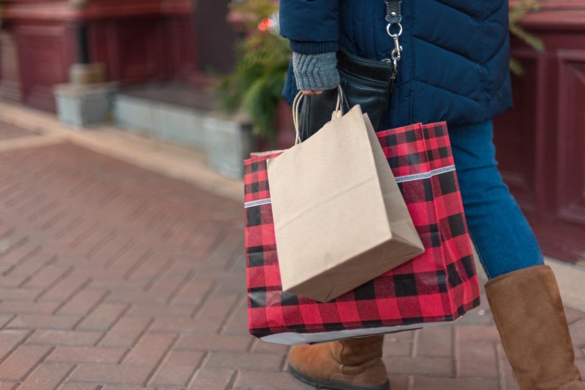Woman shopping for holiday gifts holding several festive bags at an outlet mall in North Myrtle Beach.